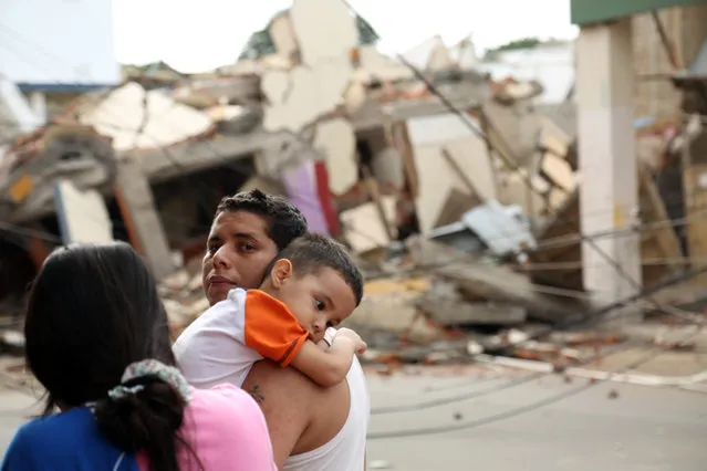 A man holds a child next to a collapsed building caused by a 7.8 earthquake in Portoviejo, Ecuador, Sunday April 17, 2016. A magnitude-7.8 quake, the strongest since 1979, hit Ecuador flattening buildings, buckling highways along its Pacific coast and killing hundreds. (Photo by Carlos Sacoto/AP Photo)