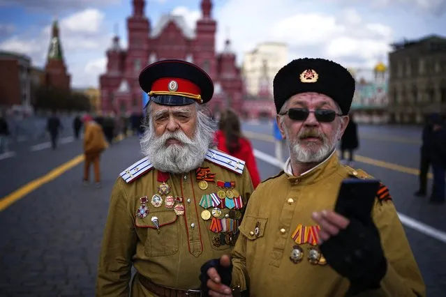 Two men in Russian Cossack uniforms pose for a selfie after visiting the Mausoleum of the Soviet founder Vladimir Lenin marking the 154th anniversary of his birth in Red Square, with the Historical Museum in the background in Moscow, Russia, Monday, April 22, 2024. (Photo by Alexander Zemlianichenko/AP Photo)