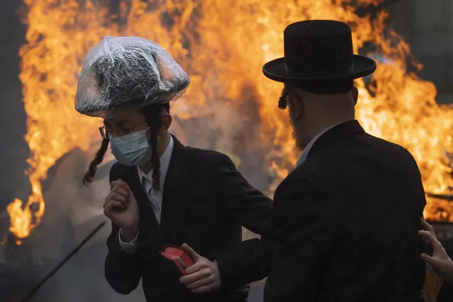 Ultra-Orthodox Jewish men and children, some wearing face mask, burn leavened items in final preparation for the Passover holiday in the ultra-Orthodox Jewish town of Bnei Brak, near Tel Aviv, Israel, Friday, March 26, 2021. Jews are forbidden to eat leavened foodstuffs during the Passover holiday that celebrates the biblical story of the Israelites' escape from slavery and exodus from Egypt. (Photo by Oded Balilty/AP Photo)