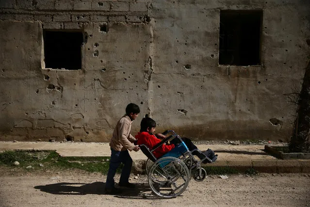 Ziad (R), 14, who has a spinal cord injury, is pushed on a wheelchair by his friend along a street in Douma, the main rebel-stronghold in eastern Ghouta on the outskirts of Damascus, Syria, February 21, 2017. (Photo by Bassam Khabieh/Reuters)