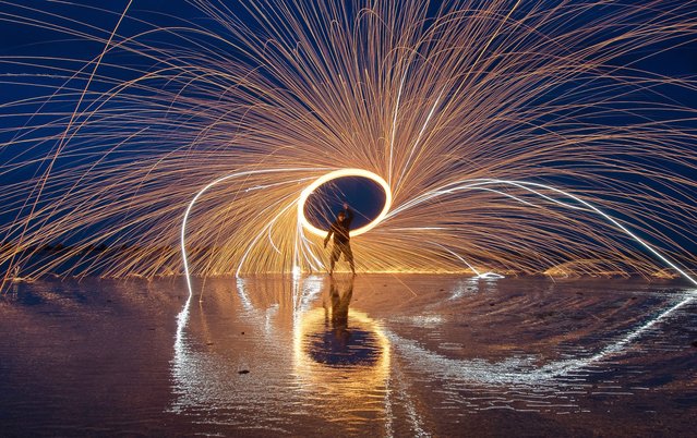 Kevin Jay, a photographer and “light painter”, sends sparks flying from burning steel wool spun around his head on a rope on Martello Beach at Clacton-on-Sea, Essex, UK on May 13, 2024. (Photo by Kevin Jay/Picture Exclusive)