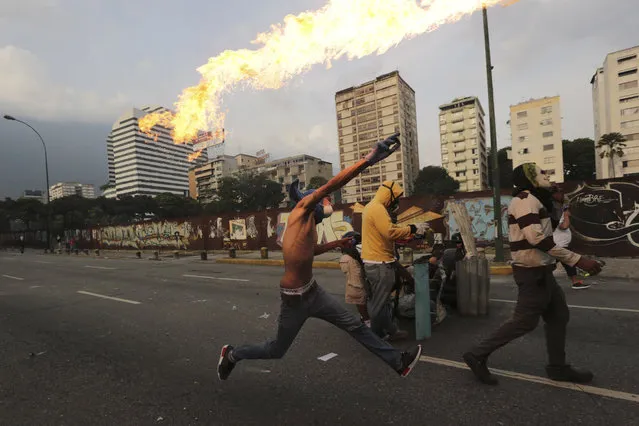 An anti-government protesters throws a molotov bomb at security forces in Caracas, Venezuela, Wednesday, April 19, 2017. (Photo by Fernando Llano/AP Photo)
