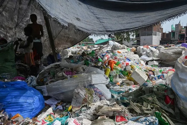 People stand next to piles of separated plastic waste in New Delhi on September 9, 2019. (Photo by Money Sharma/AFP Photo)