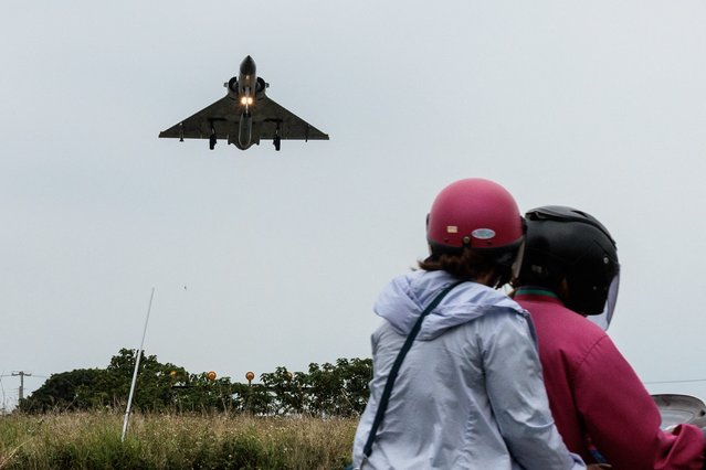 Two people ride a motorcycle as a Taiwanese Air Force Mirage 2000 fighter jet approaches for landing at an air force base in Hsinchu in northern Taiwan on May 23, 2024. China on May 23 encircled Taiwan with naval vessels and military aircraft in war games aimed at punishing the self-ruled island after its new president vowed to defend democracy. (Photo by Yasuyoshi Chiba/AFP Photo)
