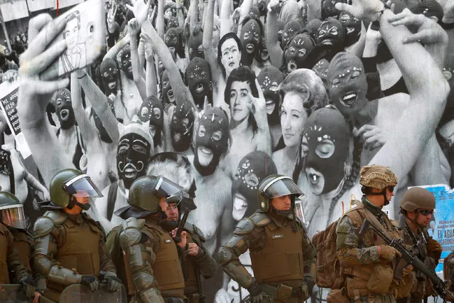 Chilean military stand in front of a mural as Anti-government demonstrators protest against cost of living increases on October 20, 2019 in Santiago, Chile. President Sebastian Piñera suspended the 3.5% subway fare hike and declared the state of emergency for the first time since the return of democracy in 1990. Protests had begun on Friday and developed into looting and arson, generating chaos in Santiago, Valparaiso and a dozen of other cities. (Photo by Marcelo Hernandez/Getty Images)