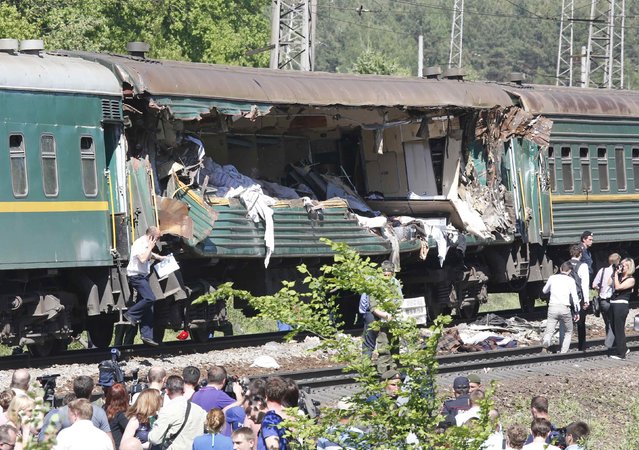 People gather near a passenger train damaged in a collision with a freight train in Moscow region May 20, 2014. The passenger train on its way to Moldova collided with a freight train near Moscow on Tuesday, killing at least four people and injuring 15, a spokeswoman for Russia's Emergencies Ministry said. The reason for the collision, near the town of Naro-Fominsk 55 km (34 miles) southwest of Moscow, was not immediately clear. (Photo by Grigory Dukor/Reuters)