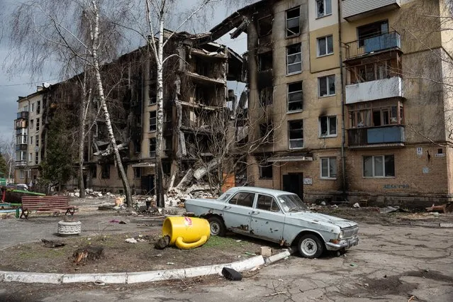 A damaged car is seen next to a heavily damaged apartment building on April 6, 2022 in Hostomel, Ukraine. Hostomel was occupied for more than a month by Russian forces as they pushed toward the Ukrainian capital, before ultimately retreating to Belarus last week. (Photo by Alexey Furman/Getty Images)