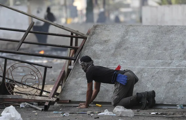 A protester takes cover during ongoing protests in downtown Baghdad, Iraq, Sunday, November 10, 2019. (Photo by Hadi Mizban/AP Photo)