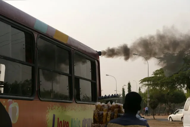 A man sells plantain chips near a bus with smoke seen from its exhaust at a bus park in Abuja, Nigeria, February 1, 2017. (Photo by Afolabi Sotunde/Reuters)