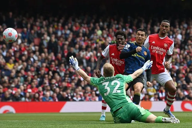 Manchester United's Portuguese striker Cristiano Ronaldo (2nd R) shoots past Arsenal's English goalkeeper Aaron Ramsdale to score their first goal during the English Premier League football match between Arsenal and Manchester United at the Emirates Stadium in London on April 23, 2022. (Photo by Glyn Kirk/AFP Photo)