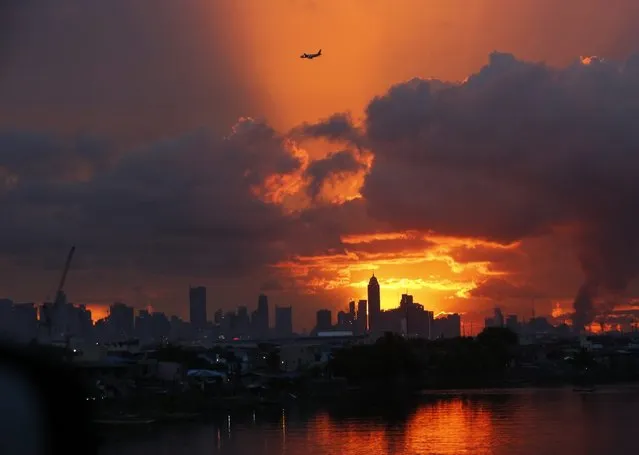 An airplane flies over the Makati financial district skyline as the sun sets in Taguig city, south of Manila, Philippines, 05 June 2016. World Environment Day (WED) is celebrated every year on 05 June to raise global awareness of the need to take positive environmental actions. (Photo by Francis R. Malasig/EPA)