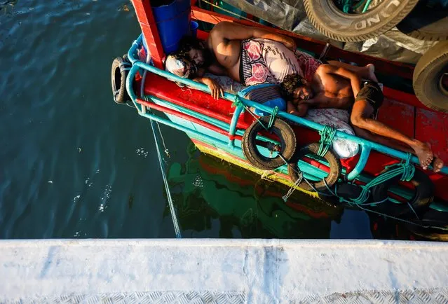 Men sleep on a fishing trawler parked at Negombo's “Lellama” fishery harbour, as fishermen and their families struggle due to a lack of diesel and a price hike over the last few months amid the country's economic crisis, in Negombo, Sri Lanka, April 16, 2022. (Photo by Navesh Chitrakar/Reuters)