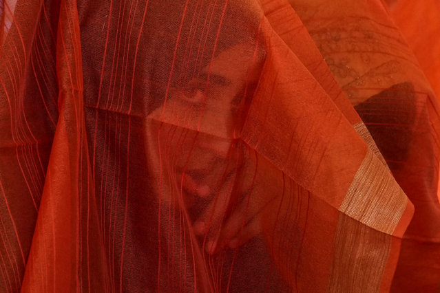 A Kashmiri Muslim bride looks through her veil during a mass wedding event in Srinagar, Indian controlled Kashmir, Thursday, June 15, 2023. Mass weddings in India are organized by social organizations primarily to help families who cannot afford the high ceremony costs as well as the customary dowry and expensive gifts that are still prevalent in many communities. (Photo by Mukhtar Khan/AP Photo)