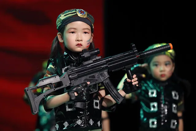 In this Friday, June 23, 2017 photo, a kindergarten student wears a military costume with a PLA badge on her hat as she performs with a toy rifle on stage during a graduation ceremony in Beijing. (Photo by Andy Wong/AP Photo)