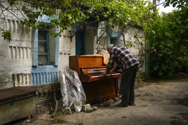 Local resident Anatolii Virko plays a piano outside a house likely damaged after a Russian bombing in Velyka Kostromka village, Ukraine, Thursday, May 19, 2022. (Photo by Francisco Seco/AP Photo)