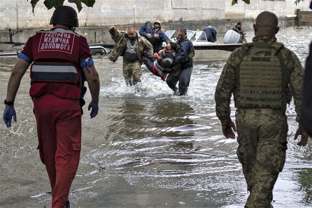 Emergency teams help rush to safety injured civilian evacuees who had came under fire from Russian forces while trying to flee by boat from the Russian-occupied east bank of a flooded Dnieper River to Ukrainian-held Kherson, on the western bank in Kherson, Ukraine on Sunday, June 11, 2023. (Photo by AP Photo/Stringer)