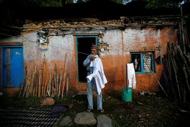 Durga Kami, 68, who is studying in the tenth grade at Shree Kala Bhairab Higher Secondary School, collects his school uniform, which has been drying in the sun outside his one-room house in Syangja, Nepal, June 4, 2016. (Photo by Navesh Chitrakar/Reuters)