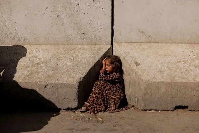A girl sits between concrete barriers in Kabul, Afghanistan on October 7, 2021. (Photo by Jorge Silva/Reuters)