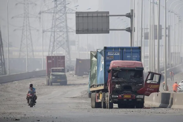 Motorcyclists ride along a highway, next to damaged trucks, near the site of the explosions at the Binhai new district in Tianjin August 13, 2015. (Photo by Jason Lee/Reuters)