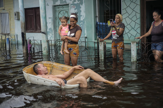 A man floats in a container on a street flooded by the passing of Hurricane Helene, in Batabano, Mayabeque province, Cuba, Thursday, September 26, 2024. (Photo by Ramon Espinosa/AP Photo)