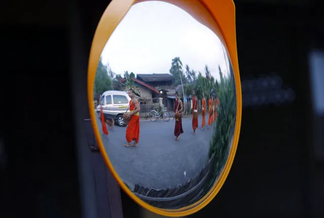 Buddhist monks collecting alms at daybreak in a morning ritual walking barefoot through the streets of the UNESCO world heritage site Luang Prabang to receive their daily food alms from tourists and Lao residents, in the Lao People's Democratic Republic, May 17, 2015. (Photo by Barbara Walton/EPA)