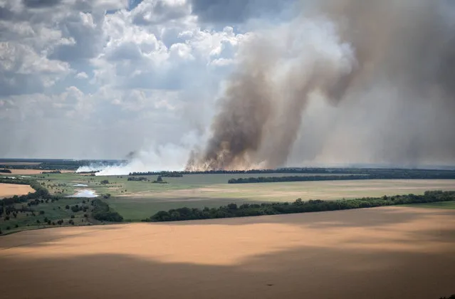 Smoke raises from the front lines where fierce battle is going between Ukrainian and Russian troops, farmer fields in the foreground, in the Dnipropetrovsk region, Ukraine, Monday, July 4, 2022. (Photo by Efrem Lukatsky/AP Photo)
