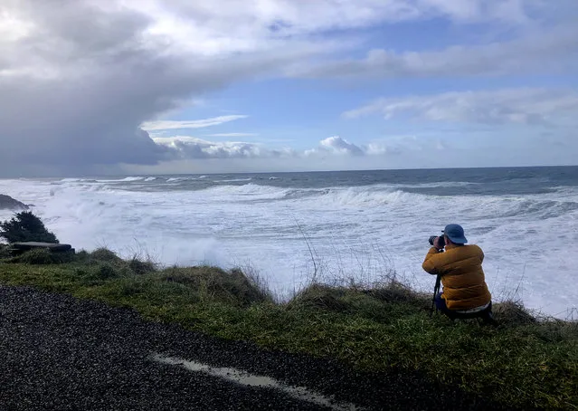 In this January 11, 2020 photo a man photographs waves crashing onto the cliffs at Rodea Point in Lincoln County, Ore. during an extreme high tide that coincided with a big winter storm. Amateur scientists are whipping out their smartphones to document the effects of extreme high tides on shore lines from the United States to New Zealand, and by doing so are helping better predict what rising sea levels due to climate change will mean for coastal communities around the world. (Photo by Gillian Flaccus/AP Photo)