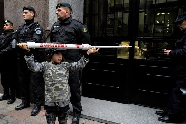 A boy holding a giant, mock syringe that reads in Spanish “sovereignty” attends a protest outside the Supreme court during a hearing where the government and Pfizer are to give more detailed information on COVID-19 vaccines for children, which was requested by a national, administrative court, in Montevideo, Uruguay, Wednesday, July 6, 2022. Meanwhile, the vaccination of children over age five is voluntarily and ongoing. (Photo by Matilde Campodonico/AP Photo)