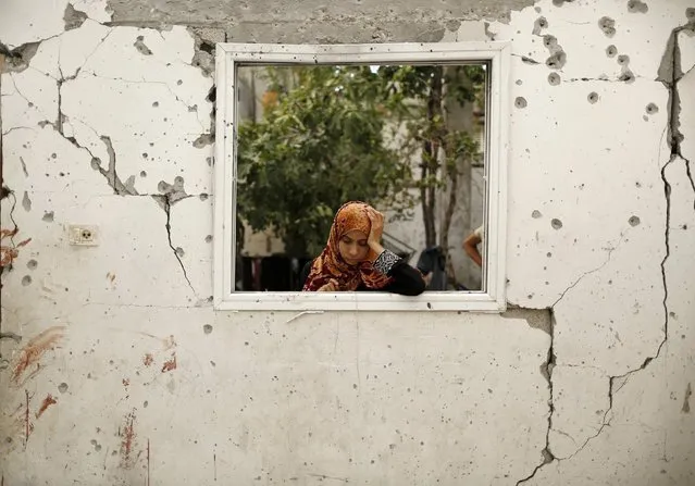 A relative reacts at a badly damaged house, which witnesses said was hit by an Israeli air strike that killed three Palestinians from the Wahdan family, as bloodstains are seen on a damaged wall in Jabaliya refugee camp in the northern Gaza Strip August 3, 2014. (Photo by Suhaib Salem/Reuters)