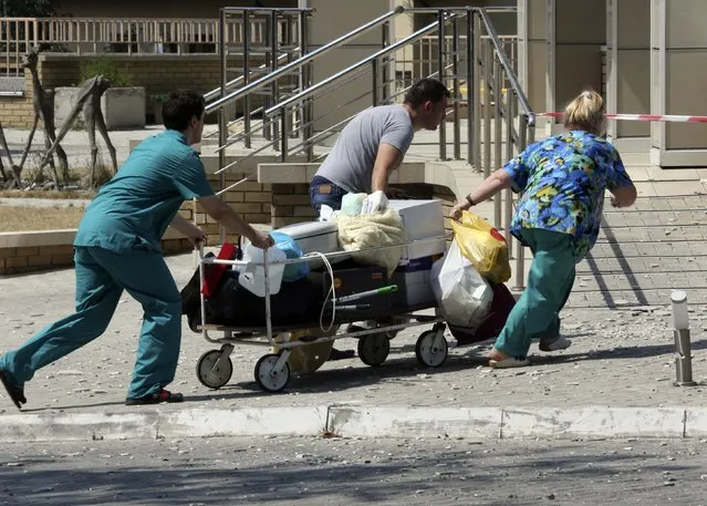 People transport office equipment from a damaged building following what locals say was shelling by Ukrainian forces in Donetsk August 7, 2014. The Ukrainian government said on Thursday it was suspending a ceasefire with separatist rebels at the crash site of the Malaysian airliner after an international recovery mission had been halted. (Photo by Sergei Karpukhin/Reuters)