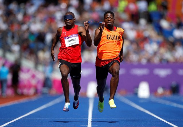 Namibia's Ananias Shikongo (L) competes with his guide during the para-men's 100m T11/12 round 1 athletics event at the Alexander Stadium, in Birmingham on day six of the Commonwealth Games in Birmingham, central England, on August 3, 2022. (Photo by John Sibley/Reuters)