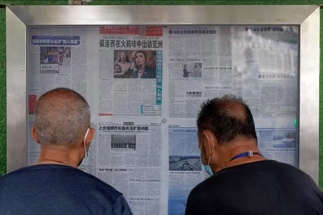 Men read the Global Times newspaper that features a front page article about U.S. House of Representatives Speaker Nancy Pelosi's Asia tour at a street display wall in Beijing, China, August 1, 2022. The front page headline reads: “Pelosi visits Asia in the smell of gunpowder”. (Photo by Thomas Peter/Reuters)