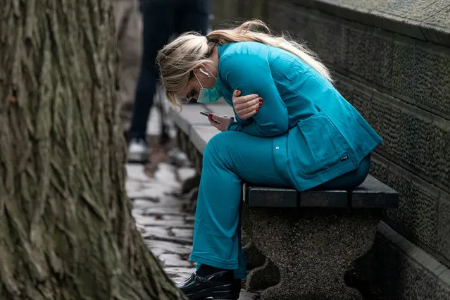 A healthcare worker sits on a bench near Central park in the Manhattan borough of New York City, U.S., March 30, 2020. (Photo by Jeenah Moon/Reuters)
