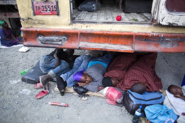 In this July 24, 2016 photo, pilgrims sleep under a school bus during the annual Voodoo celebration in Plaine-du-Nord, Haiti. While some sleep in a public school, others sleep on the side of the road and the front yards of local homes due to a lack of accommodations. (Photo by Dieu Nalio Chery/AP Photo)