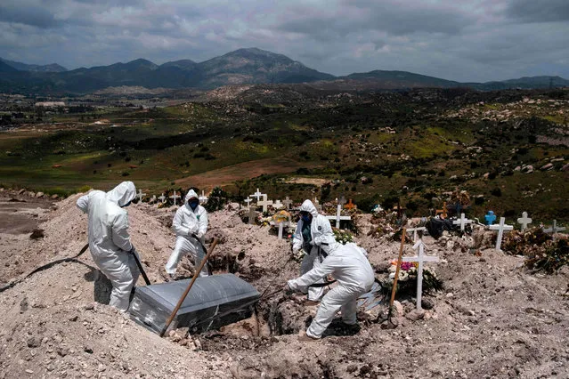 Cementery workers wearing protective gear bury an unclaimed COVID-19 coronavirus victim, at the Municipal cementery No. 13 in Tijuana, Baja California state, Mexico, on April 21, 2020. (Photo by Guillermo Arias/AFP Photo)