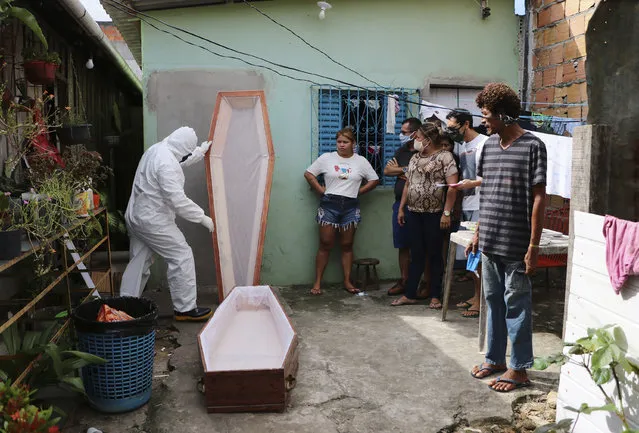 A funeral worker wearing protection gear prepares a coffin to remove thebody of Raimundo Costa do Nascimento, 86, who died at home amid the new coronavirus pandemic in Sao Jorge, Manaus, Brazil, Thursday, April 30, 2020. Family members had to wait 10 hours for funerary services to come pick up his body. (Photo by Edmar Barros/AP Photo)