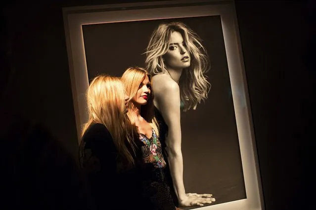 Martha Hunt, center, stands in front of a photo of herself at a gallery party thrown by Victoria's Secret during New York Fashion Week, September 10, 2014. The gala celebrated photographer Russell James' new book, “Angels”. (Photo by Julie Glassberg/The New York Times)