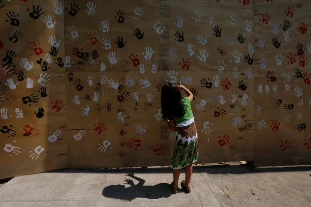 A child places her painted hand on a mural in honor to the victims who died in the earthquake, to mark the one month anniversary of the devastating quake that left over 300 dead and destroyed large swathes of neighborhoods and multifamily buildings in Mexico City on October 19, 2017. (Photo by Carlos Jasso/Reuters)