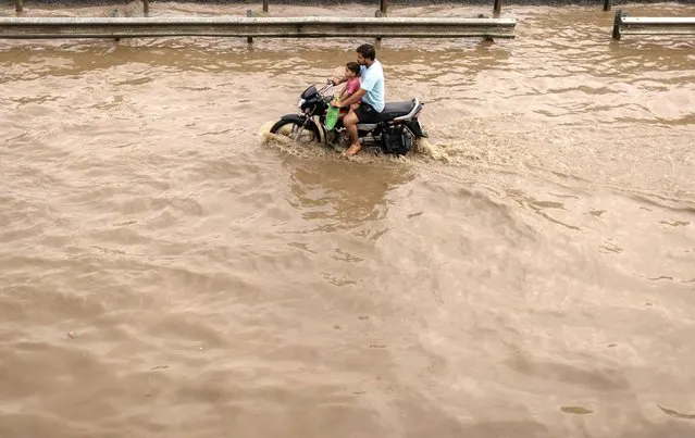 A man rides his motorbike with his son on a flooded street after heavy rains in Gurugram, on the outskirts of New Delhi, India on September 23, 2022. (Photo by Adnan Abidi/Reuters)