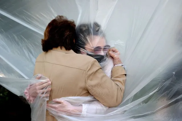 Olivia Grant (R) hugs her grandmother, Mary Grace Sileo through a plastic drop cloth hung up on a homemade clothes line during Memorial Day Weekend on May 24, 2020 in Wantagh, New York. It is the first time they have had contact of any kind since the coronavirus COVID-19 pandemic lockdown started in late February. (Photo by Al Bello/Getty Images)