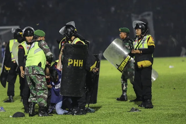 Police officers arrest a fan on the pitch during a clash between fans at Kanjuruhan Stadium in Malang, East Java, Indonesia 02 October 2022. At least 127 people including police officers were killed mostly in stampedes after a clash between fans of two Indonesian soccer teams, according to the police. (Photo by H. Prabowo/EPA/EFE)