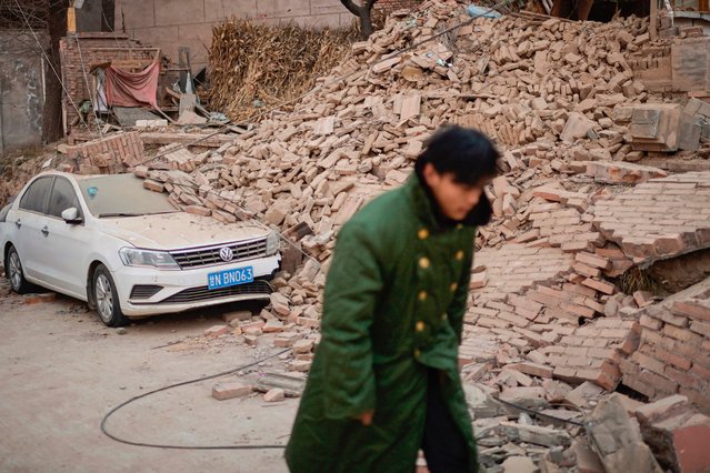 A man walks past a collapsed house in Dahejia in Jishishan County in northwest China's Gansu province on December 20, 2023. Survivors of China's deadliest earthquake in years huddled in aid tents on December 20 after overnight temperatures plunged well below zero, with the death toll rising to 131. (Photo by Pedro Pardo/AFP Photo)