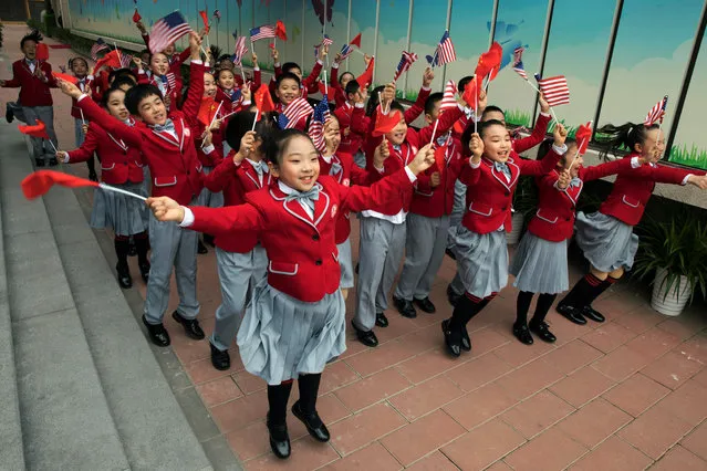 Students wave US and Chinese flags as they send off US First Lady Melania Trump and China's First Lady Peng Liyuan after their visit to the Banchang Primary School in Beijing on November 9, 2017. China's President Xi Jinping hosted US President Donald Trump at the imposing Great Hall of the People, next to Tiananmen Square, for the main event of the US president's five-nation tour of Asia. (Photo by Ng Han Guan/AFP Photo)