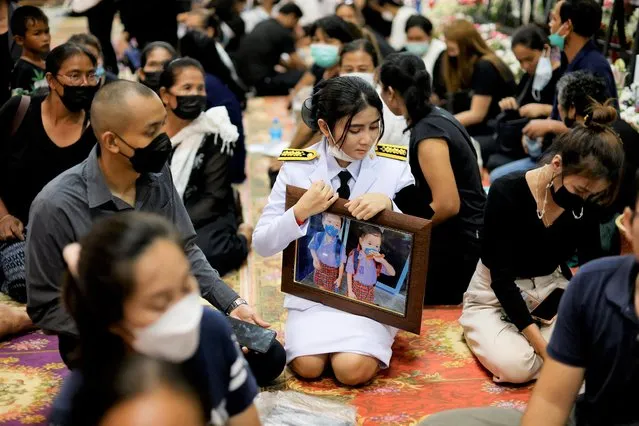 A woman holds a picture as people pray during a funeral, following a mass shooting at a day care centre, at Wat Rat Samakee, in the town of Uthai Sawan, in the province of Nong Bua Lam Phu, Thailand on October 9, 2022. (Photo by Jorge Silva/Reuters)