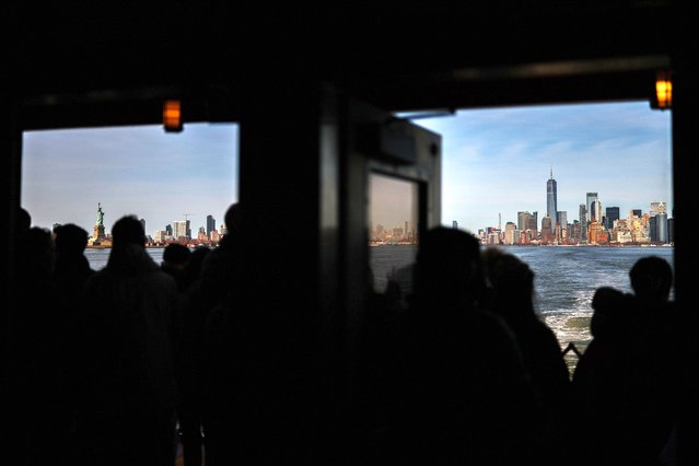 Passengers ride the Staten Island Ferry from Manhattan to Staten Island, as One World Trade Center (also known as the Freedom Tower) in midtown Manhattan and the Statue of Liberty loom in the distance in New York City, March 23, 2024. (Photo by Charly Triballeau/AFP Photo)