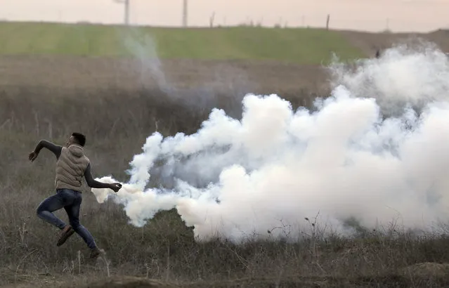 A Palestinian protester throws back a teargas canister fired by Israeli troops during clashes on the Israeli border with Gaza, Sunday, December 10, 2017. (Photo by Khalil Hamra/AP Photo)