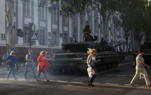 Local citizens cross a road as pro-Russian militants sit on tanks during their rehearsal for the Victory Day parade in downtown Donetsk, Ukraine, 03 May 2017. The self-proclaimed Donetsk People's Republic inhabitants will mark the 72th anniversary of the then Soviet Red Army victory over Nazi-Germany in WWII on 09 May 2017. (Photo by Alexander Ermochenko/EPA)