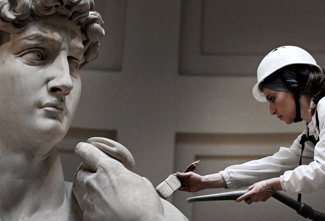 Italian restorer Eleonora Pucci cleans Michelangelo's statue of David using a backpack vacuum and synthetic fibre brush at the Galleria dell'Accademia, in Florence on February 19, 2024. Michelangelo's masterpiece received a delicate beauty treatment on Monday, part of routine maintenance on one of the world's most recognisable nudes. Every two months, the marble sculpture of a muscular and steely-eyed David – completed by a 29-year-old Michelangelo in 1504 – undergoes the careful cleaning from his home within Florence's Accademia Gallery, where it has resided for over 150 years. (Photo by Tiziana Fabi/AFP Photo)