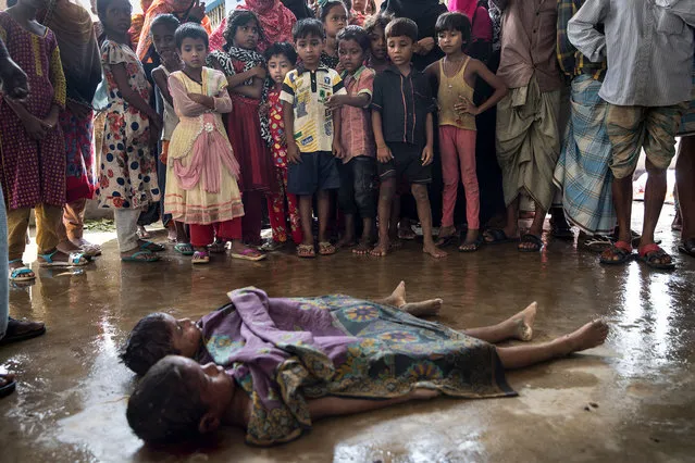 Children watch in Inani, Bangladesh on September 29, 2017, as the bodies of children are prepared for the funeral after a boat sunk in rough seas off the coast of Bangladesh carrying over 100 people . Seventeen survivors were found along with the bodies of 20 women and children with over 50 missing. Over a half a million Rohingya refugees have fled into Bangladesh from the horrific violence in Rakhine state in Myanmar causing a humanitarian crisis. (Photo by Paula Bronstein/Getty Images)