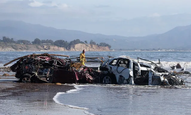 Fremont City Firefighter Jordan Castro checks vehicles that had been washed into the Pacific Ocean as he conducts search and rescue efforts after heavy rains caused deadly mudslides in Montecito, California, USA, 10 January 2018. A rain storm in southern California has destroyed several homes and killed at least 15 people in Montecito, California and closed a 35 mile stretch of the 101 freeway. (Photo by Mike Nelson/EPA/EFE)